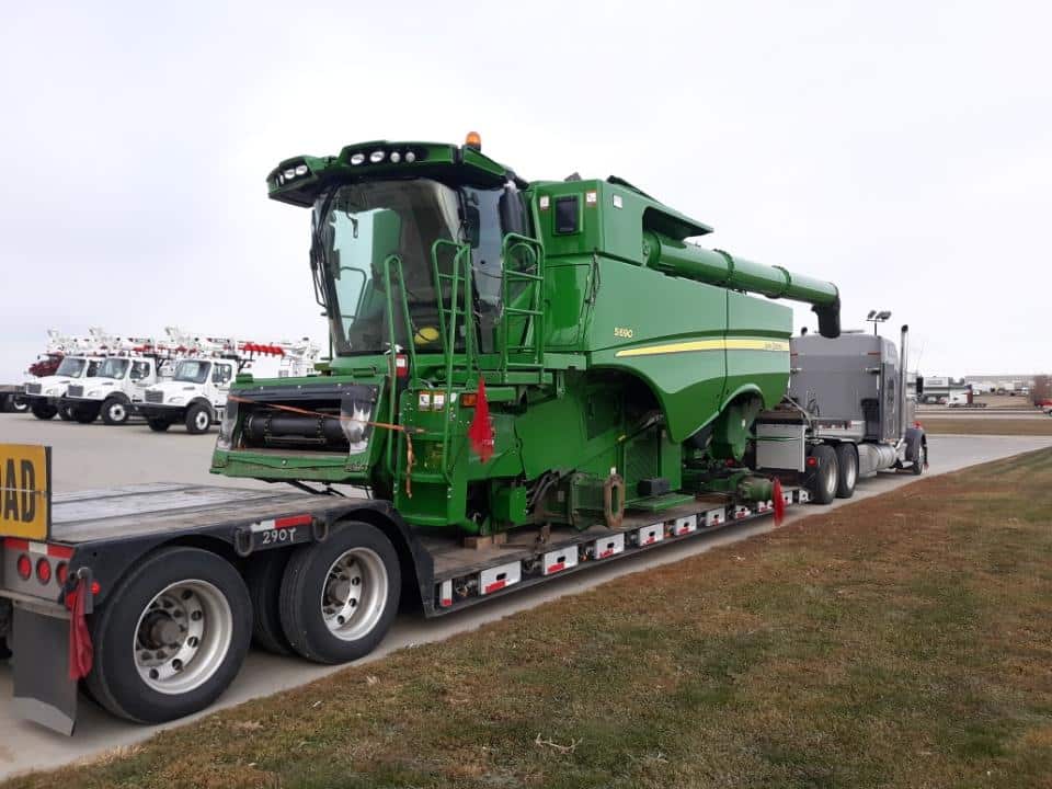 John Deere Combine transported on a lowboy trailer