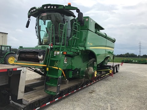 John Deere combine loaded for transport on a lowboy trailer