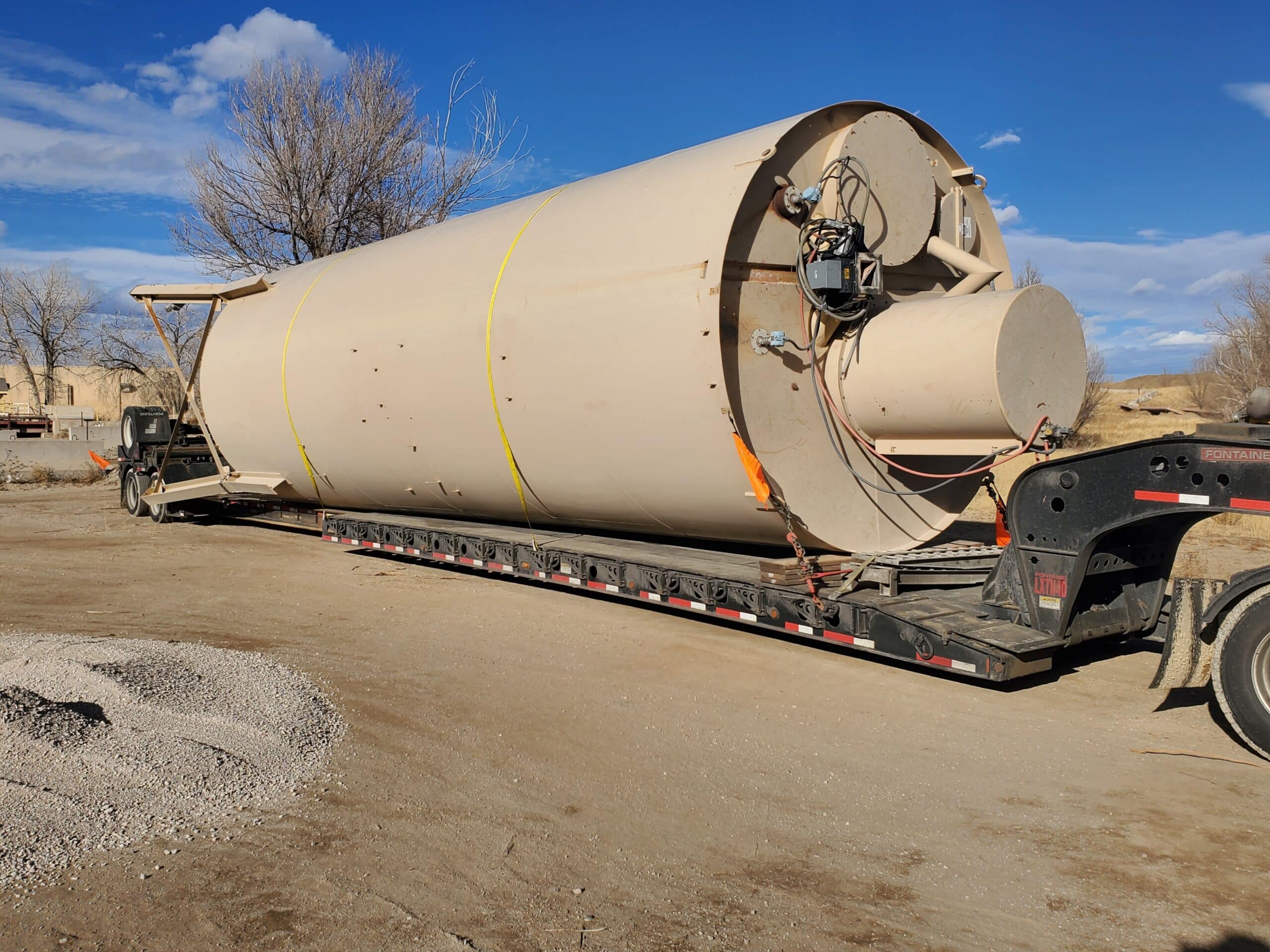 Silo tank prepared for transport on a lowboy trailer